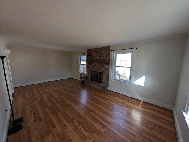 unfurnished living room featuring visible vents, wood finished floors, crown molding, baseboards, and a brick fireplace