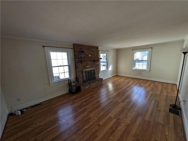 unfurnished living room featuring a brick fireplace, wood finished floors, baseboards, and ornamental molding