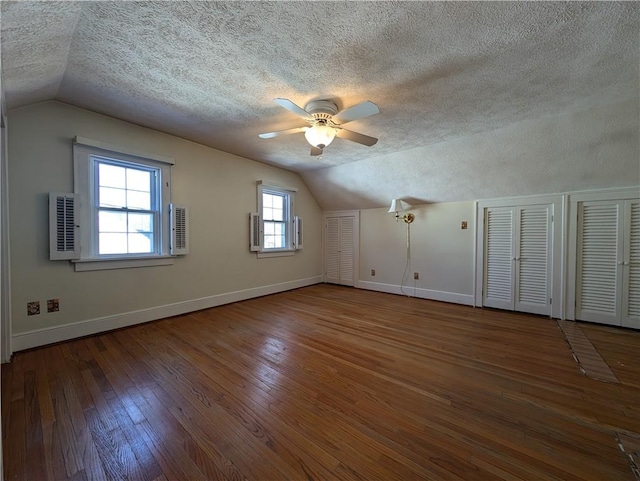 additional living space featuring lofted ceiling, baseboards, wood-type flooring, and a textured ceiling