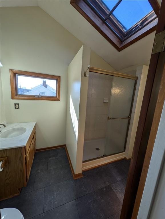 full bath featuring vanity, lofted ceiling with skylight, baseboards, and a stall shower