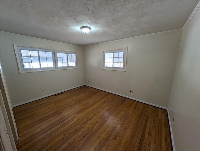 spare room featuring baseboards, wood-type flooring, a textured ceiling, and visible vents