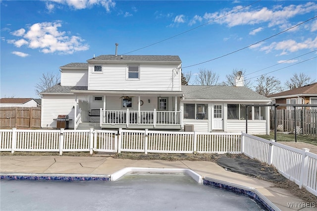 rear view of property with a porch, a fenced front yard, and a sunroom