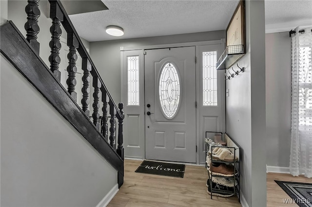 entryway featuring a wealth of natural light, stairs, and light wood-style floors