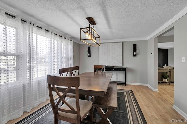 dining area with crown molding, light wood-style flooring, and a textured ceiling