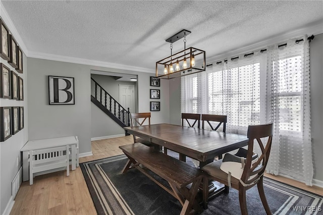 dining space with stairway, baseboards, light wood-style floors, and a textured ceiling