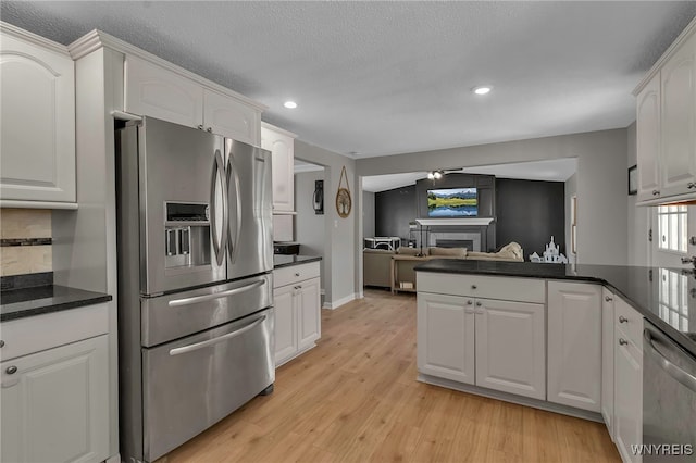 kitchen with white cabinetry, stainless steel appliances, light wood-style floors, and a fireplace