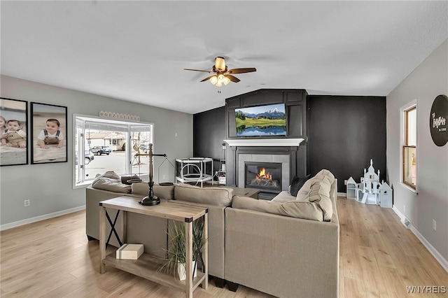 living area with lofted ceiling, light wood-type flooring, baseboards, and ceiling fan