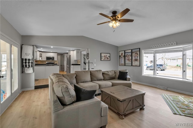 living area with a ceiling fan, visible vents, baseboards, vaulted ceiling, and light wood-type flooring