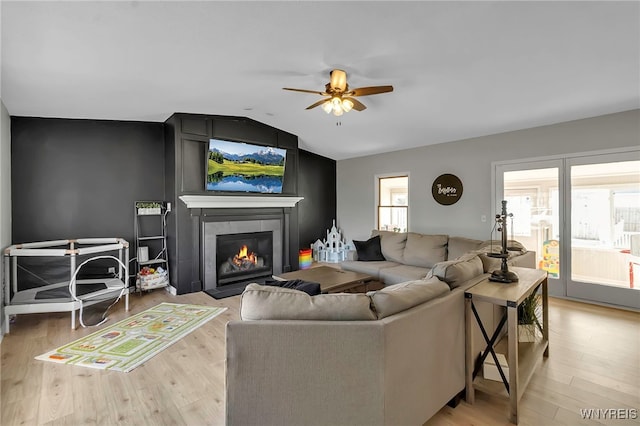 living room with light wood finished floors, a fireplace, a ceiling fan, and vaulted ceiling