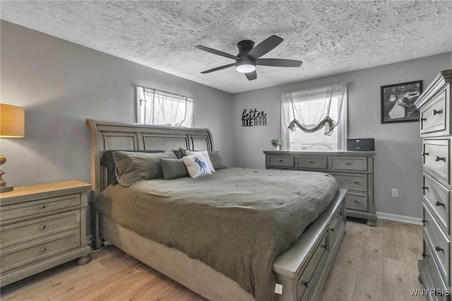 bedroom with multiple windows, a textured ceiling, a ceiling fan, and light wood finished floors