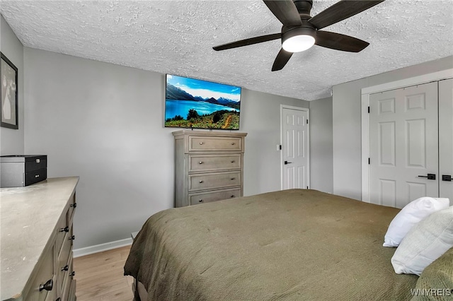 bedroom with baseboards, a textured ceiling, a ceiling fan, and light wood finished floors