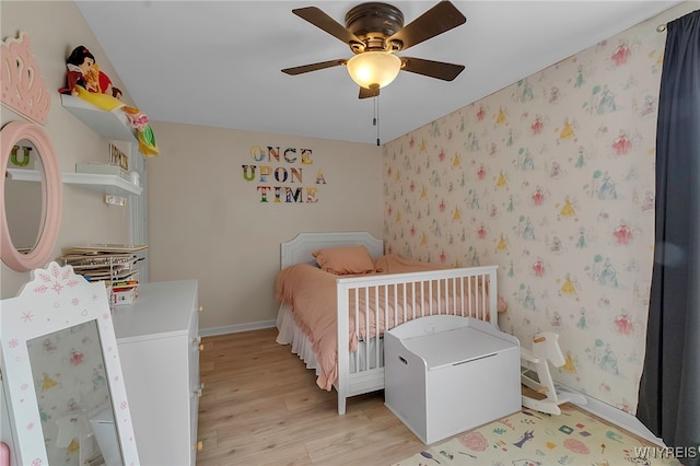 bedroom with baseboards, ceiling fan, wallpapered walls, and light wood-style floors