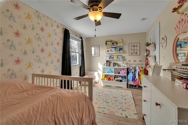 bedroom featuring light wood-style flooring, wallpapered walls, and ceiling fan