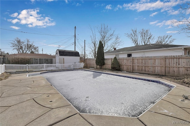 view of swimming pool featuring a fenced backyard, a shed, a patio area, and an outdoor structure