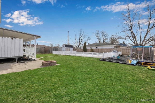 view of yard with a patio, a fire pit, a trampoline, and a fenced backyard