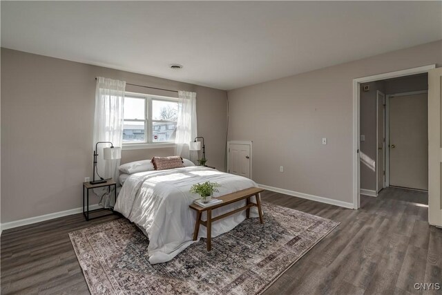 bedroom featuring visible vents, baseboards, and dark wood-style floors