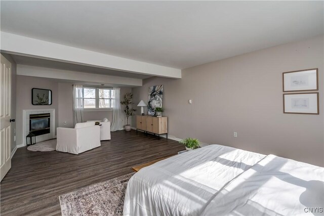 bedroom with baseboards, dark wood-type flooring, and a tiled fireplace