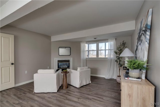 living room featuring baseboards, wood finished floors, and a tiled fireplace