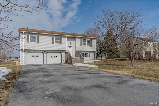 split foyer home with aphalt driveway, an attached garage, and a front yard