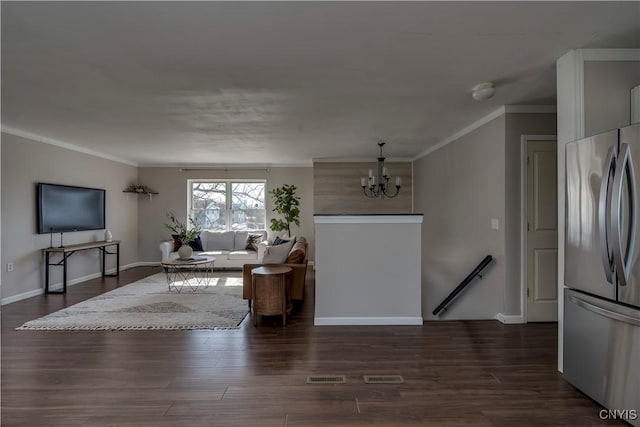 living room with dark wood finished floors, a chandelier, and ornamental molding