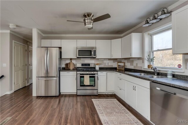 kitchen featuring stainless steel appliances, dark countertops, dark wood-style floors, and white cabinetry