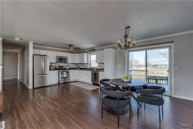 dining area with ceiling fan with notable chandelier, crown molding, dark wood-type flooring, and baseboards