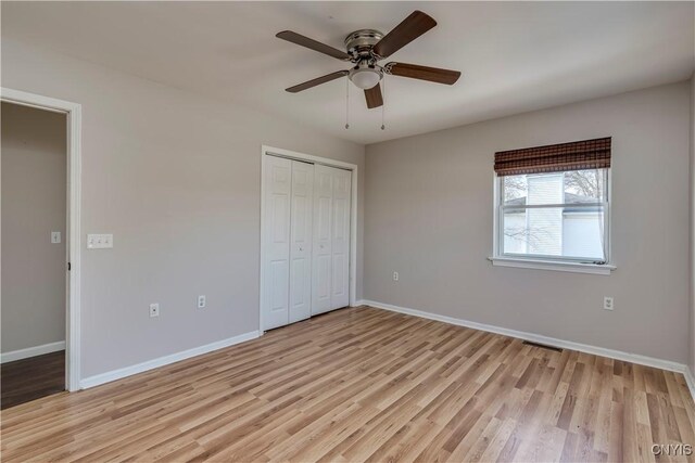 unfurnished bedroom featuring a ceiling fan, visible vents, baseboards, a closet, and light wood-type flooring