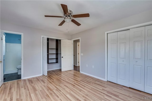 unfurnished bedroom featuring baseboards, two closets, ensuite bathroom, and light wood-style floors