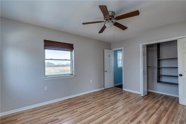 unfurnished bedroom with a closet, baseboards, light wood-style flooring, and a ceiling fan