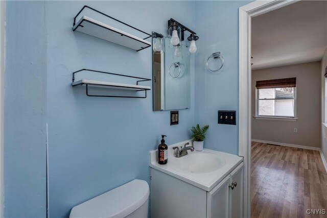 half bathroom with vanity, toilet, and wood finished floors