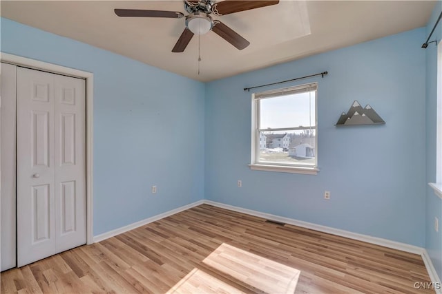 unfurnished bedroom featuring wood finished floors, visible vents, a closet, and baseboards