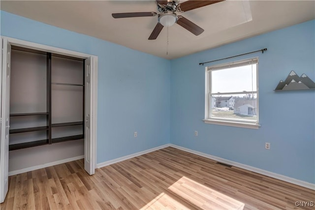 unfurnished bedroom with wood finished floors, visible vents, baseboards, ceiling fan, and a closet