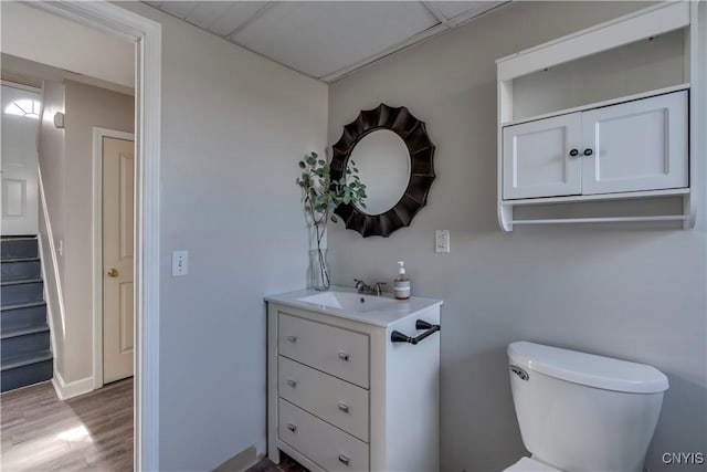 half bathroom with toilet, wood finished floors, and vanity