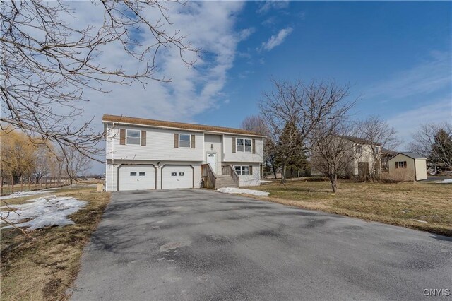 bi-level home featuring a front yard, a garage, and driveway