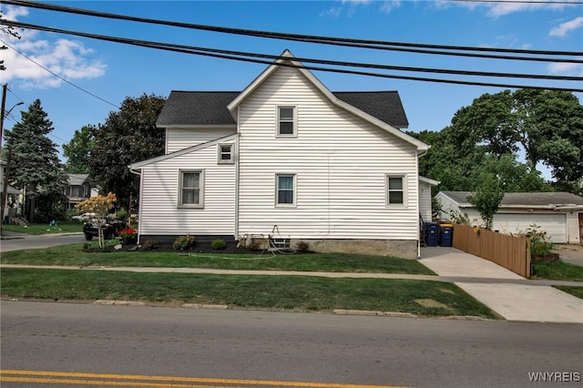 view of side of property with a yard, fence, and a shingled roof