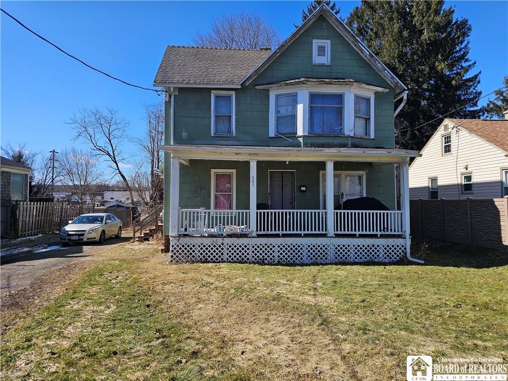 view of front of property with a front yard, fence, covered porch, and roof with shingles