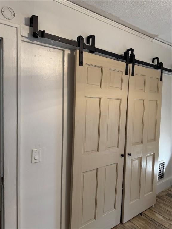 interior details with a barn door, wood finished floors, and visible vents