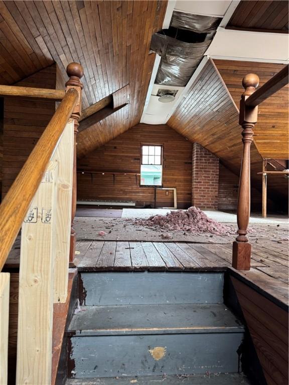 stairs with wooden walls, wooden ceiling, and lofted ceiling