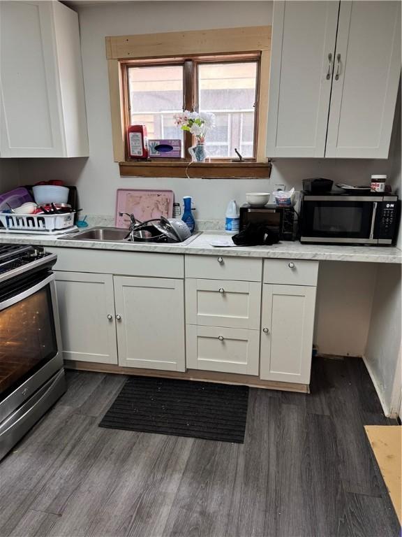 kitchen with dark wood-style floors, white cabinetry, stainless steel appliances, and light countertops