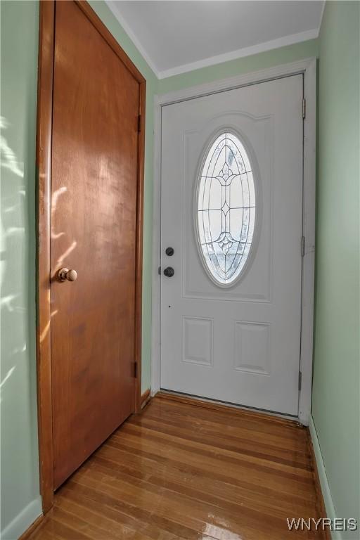 entrance foyer featuring wood finished floors, baseboards, and ornamental molding