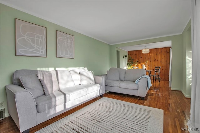 living room featuring wood walls, baseboards, ornamental molding, and wood finished floors