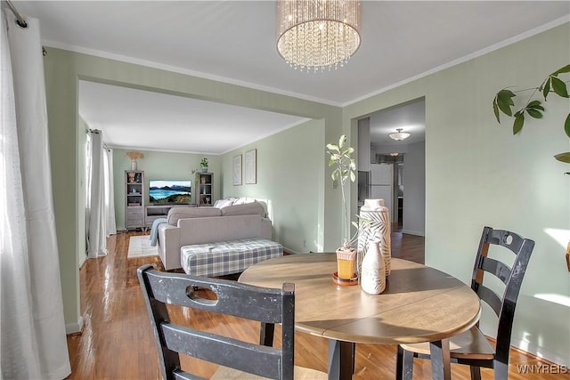 dining room featuring a chandelier, crown molding, and wood finished floors