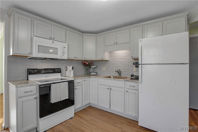 kitchen featuring a sink, decorative backsplash, white appliances, and light wood finished floors