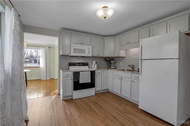 kitchen featuring a sink, white appliances, tasteful backsplash, and light wood-style flooring