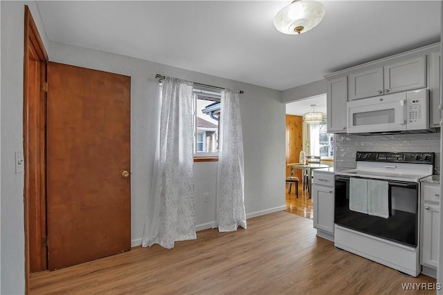 kitchen with light wood finished floors, range with electric stovetop, light countertops, decorative backsplash, and white microwave