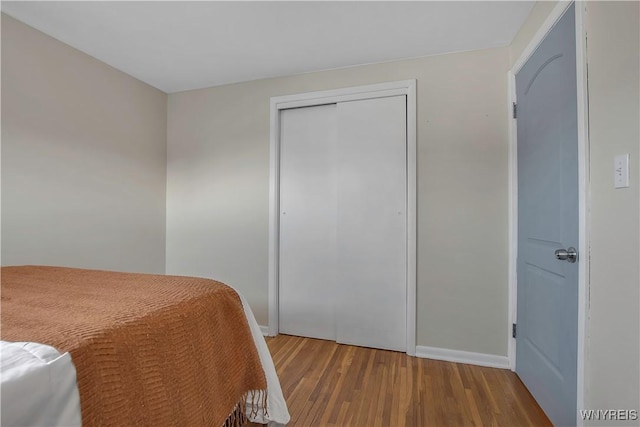 bedroom with wood finished floors, a closet, and baseboards