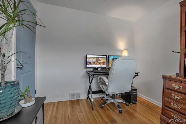 office space with wood finished floors, visible vents, and baseboards