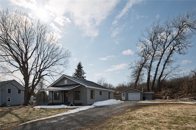 view of front of property featuring an outbuilding, driveway, a porch, a detached garage, and metal roof