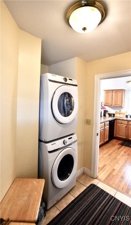 laundry area featuring laundry area, stacked washer and clothes dryer, and light wood-style floors