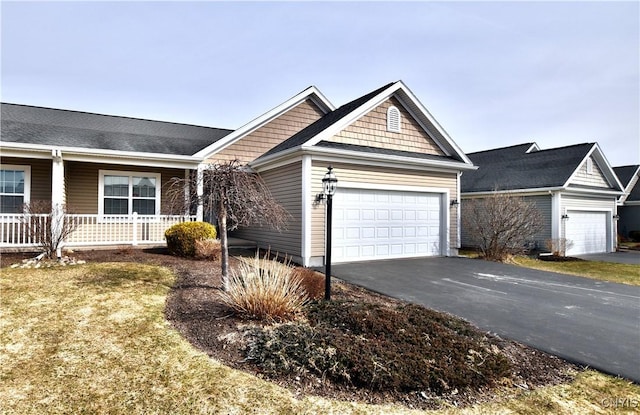 view of front facade featuring aphalt driveway, an attached garage, and covered porch